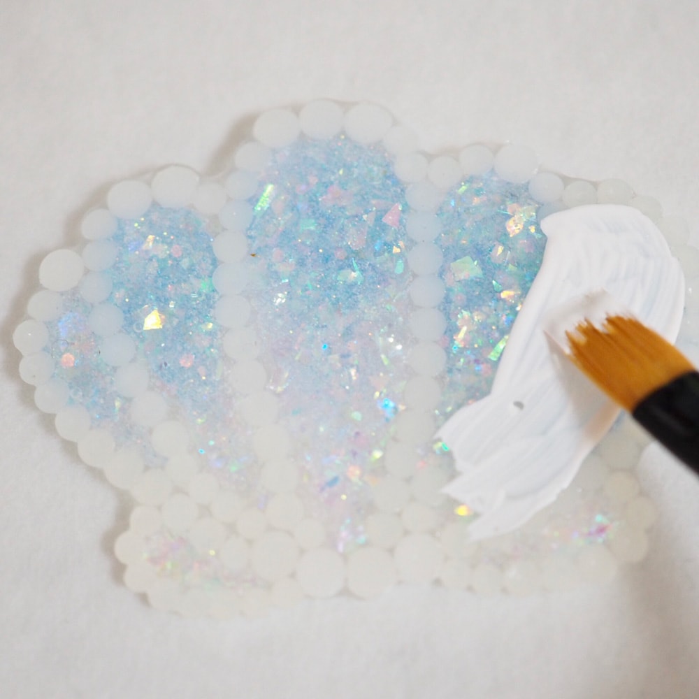 8.貝殻をクリアファイルから剥がし、裏面に白のアクリル絵の具を塗ります。(パズルに貼った際に絵柄が透けるのを防ぐため)