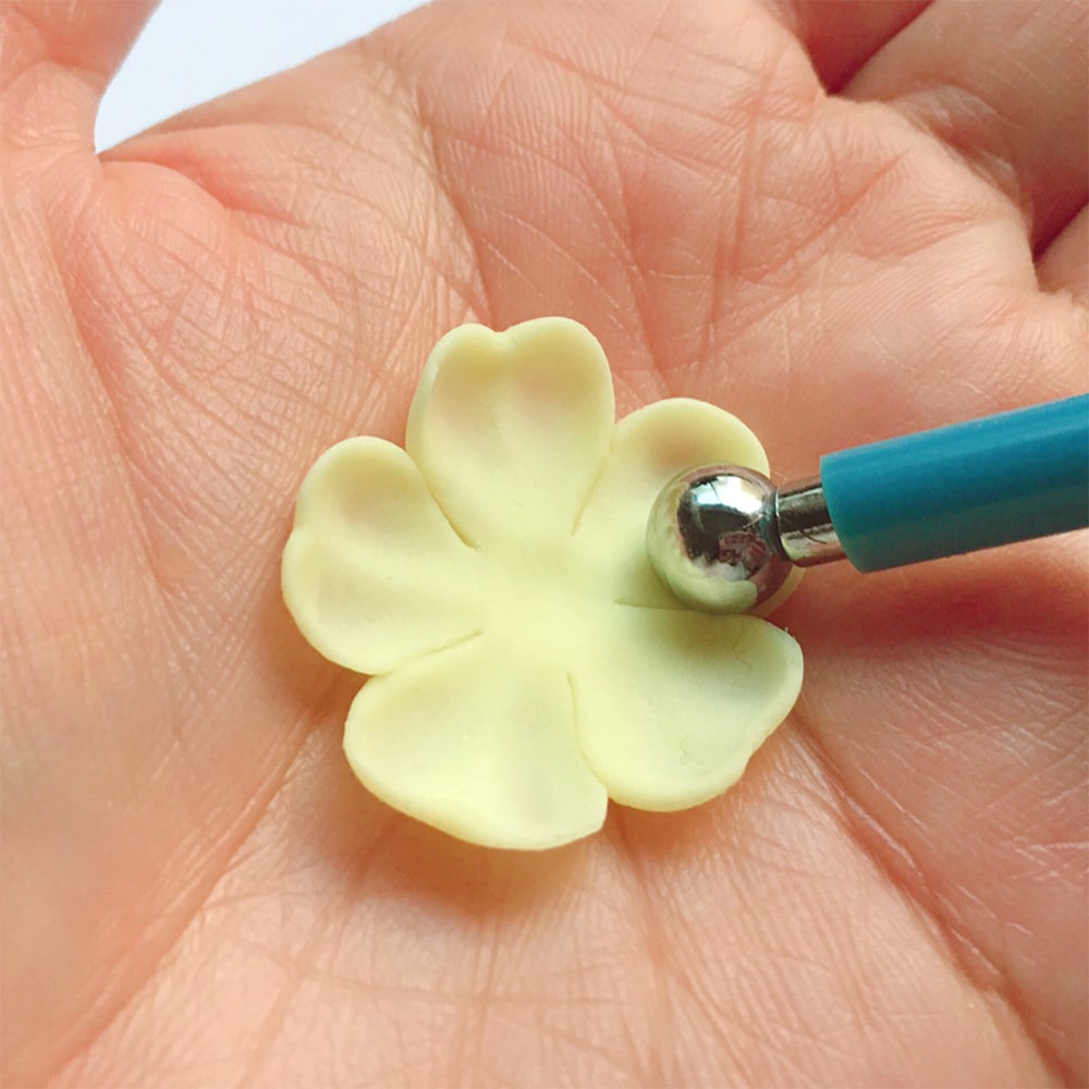 7.花弁状になった粘土を手の平にのせ、更に丸め棒を使い花弁らしくなる様に押し付けカーブを付ける。